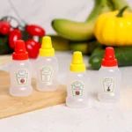Quattro mini flaconi spremibili per condimenti sul piano della cucina con verdure fresche