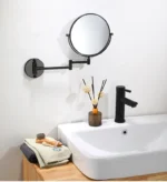 Specchio ingranditore da parete esteso sopra un rubinetto nero del lavabo
