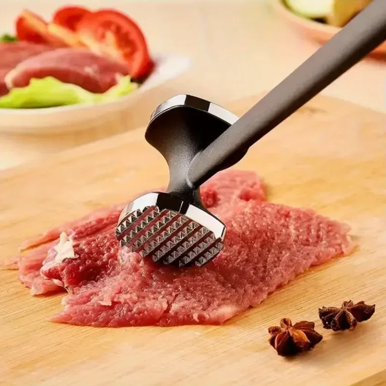 Batticarne su carne cruda su un tagliere in legno