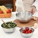 Ciotole in acciaio inossidabile con insalata e pomodori in cucina