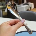 Cucchiaio in acciaio inossidabile lucidato a specchio tenuto in mano